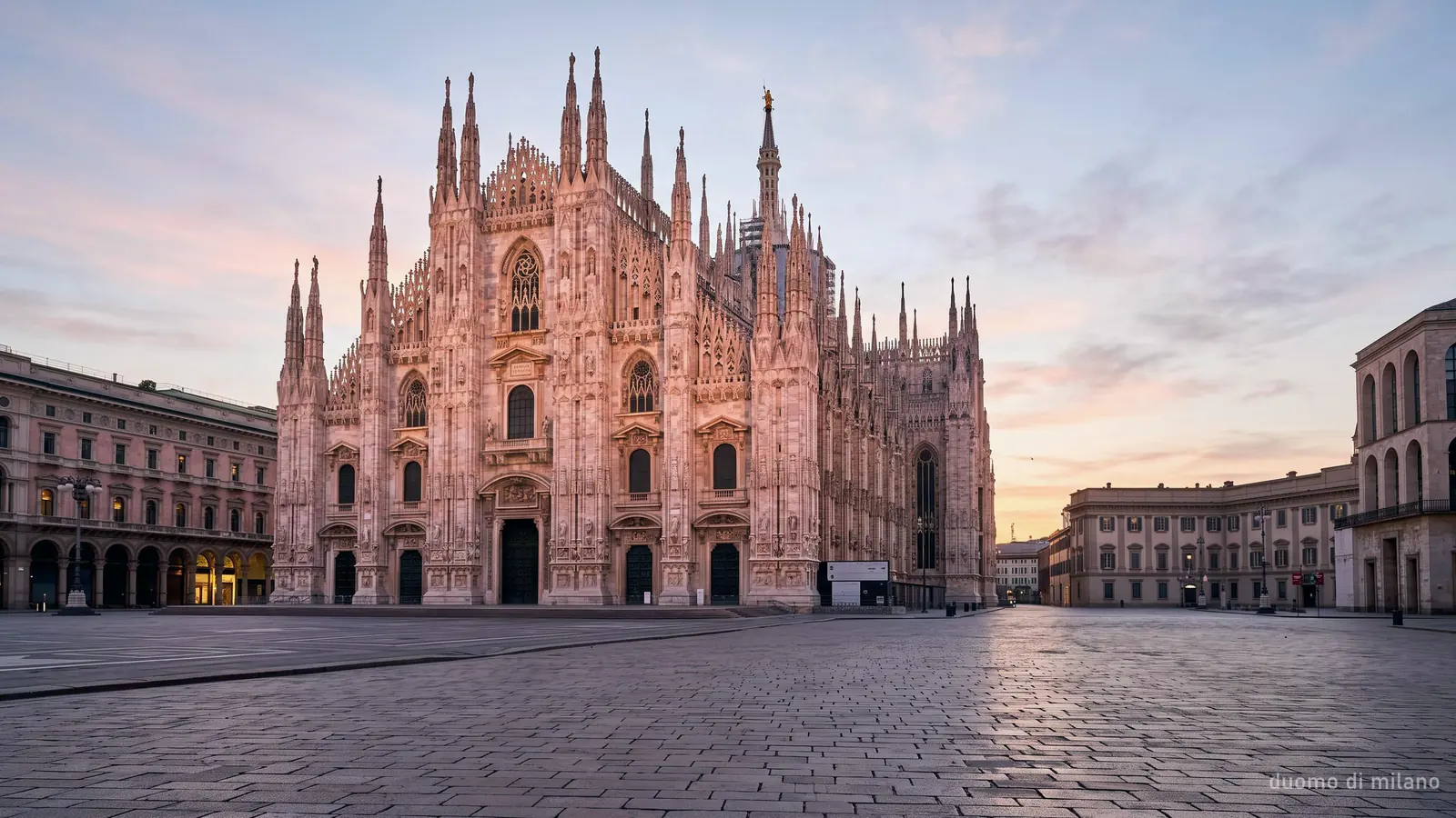 The Duomo di Milano at sunrise: the west facade across an empty Piazza del Duomo in warm early light